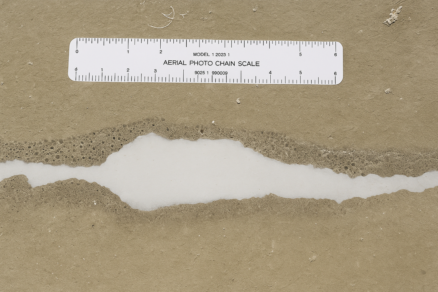 Ruler on a beach with sand and water.