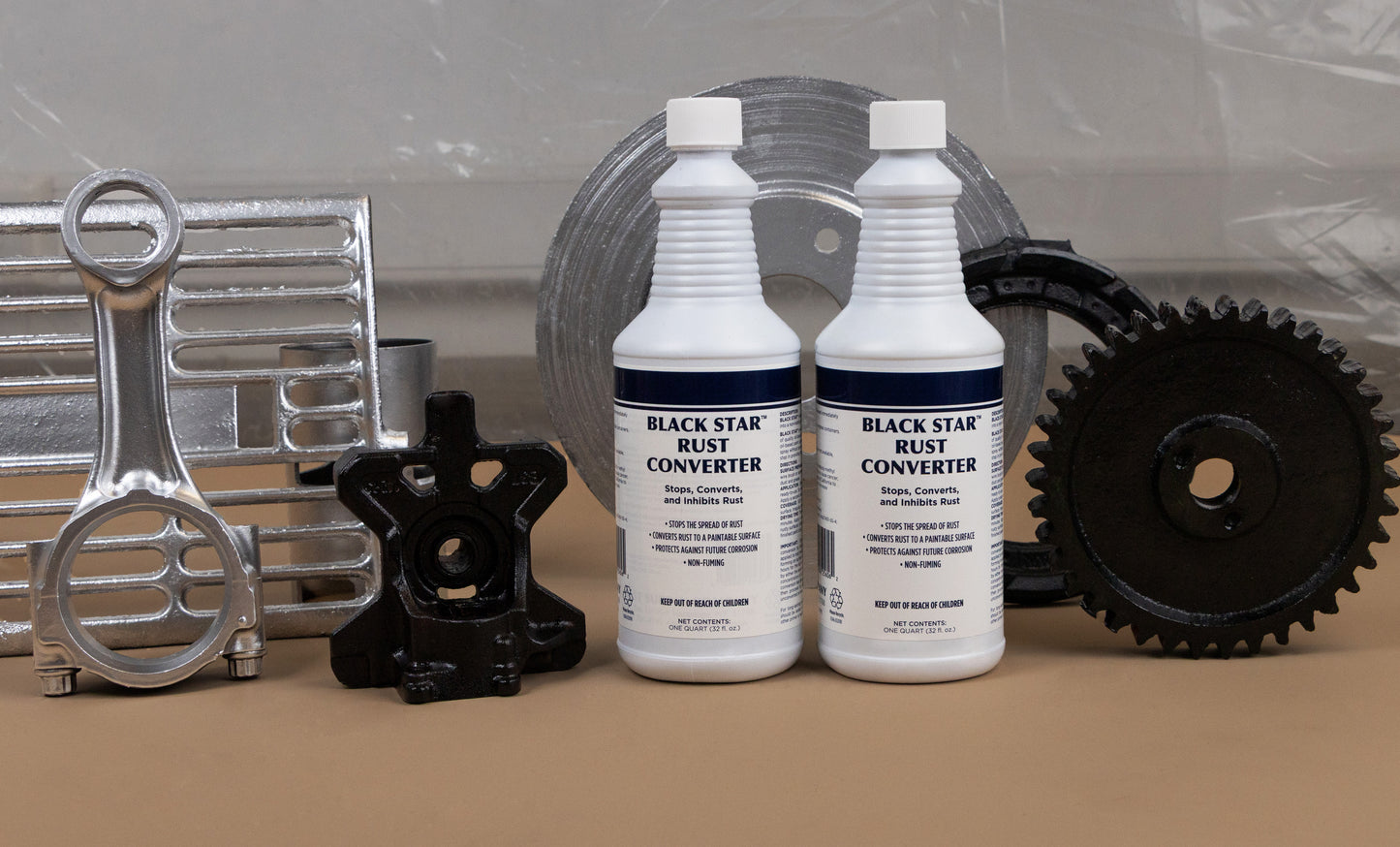 Two bottles of Black Star Rust Converter displayed alongside various restored and clean metal parts, including gears, a brake rotor, and automotive components.