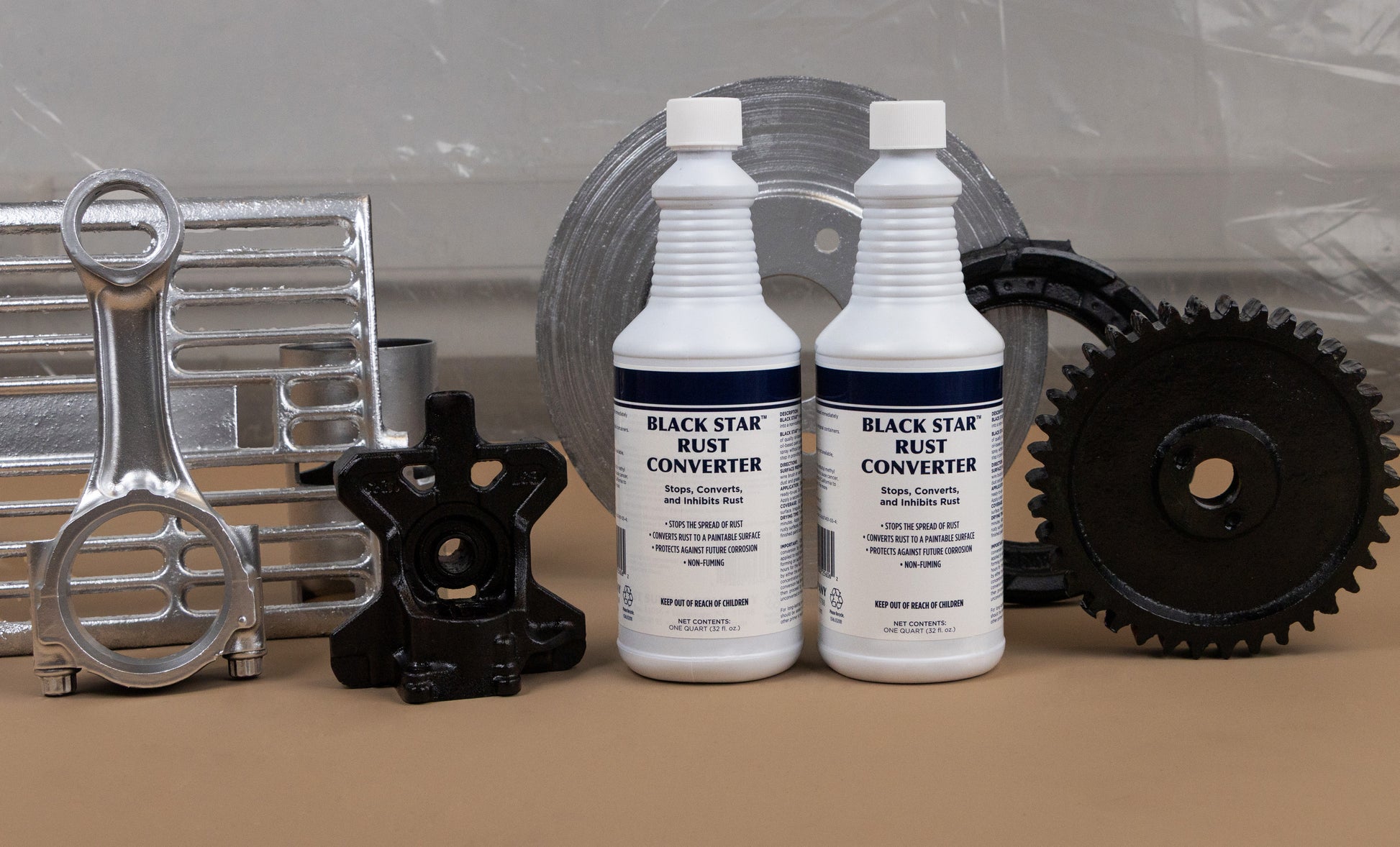 Two bottles of Black Star Rust Converter displayed alongside various restored and clean metal parts, including gears, a brake rotor, and automotive components.