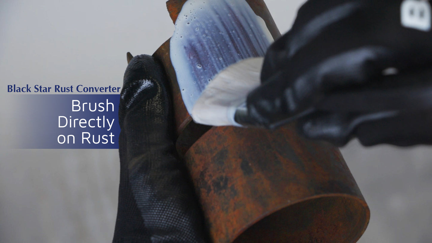 Gloved hands applying Black Star Rust Converter with a brush onto a rusty cylindrical metal surface.