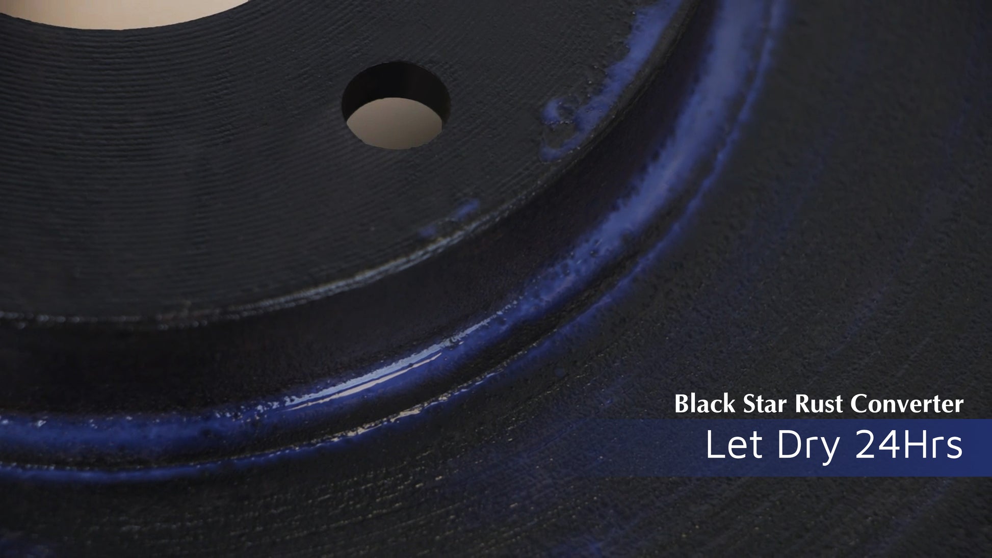 Close-up of a metal surface coated with Black Star Rust Converter, showing a glossy blue-black finish with text indicating to let it dry for 24 hours